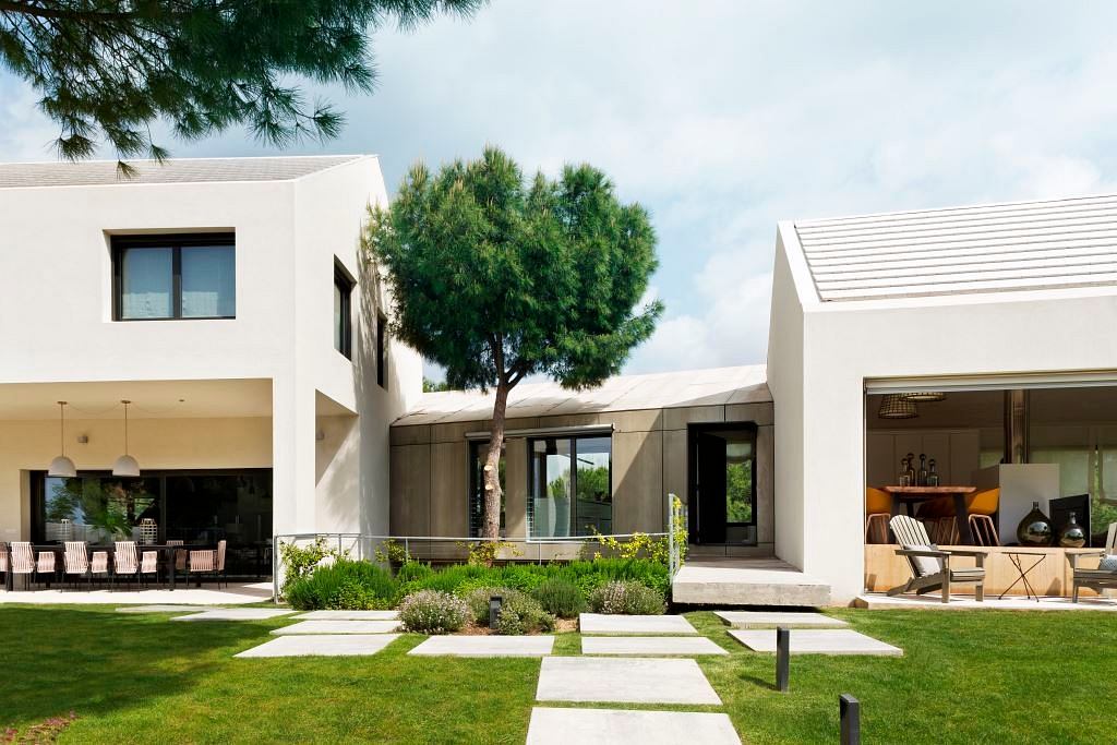 Modern house with large windows, white walls, and a landscaped garden.