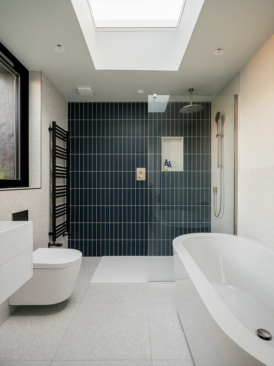 A modern bathroom with a freestanding tub, walk-in shower, and tiled