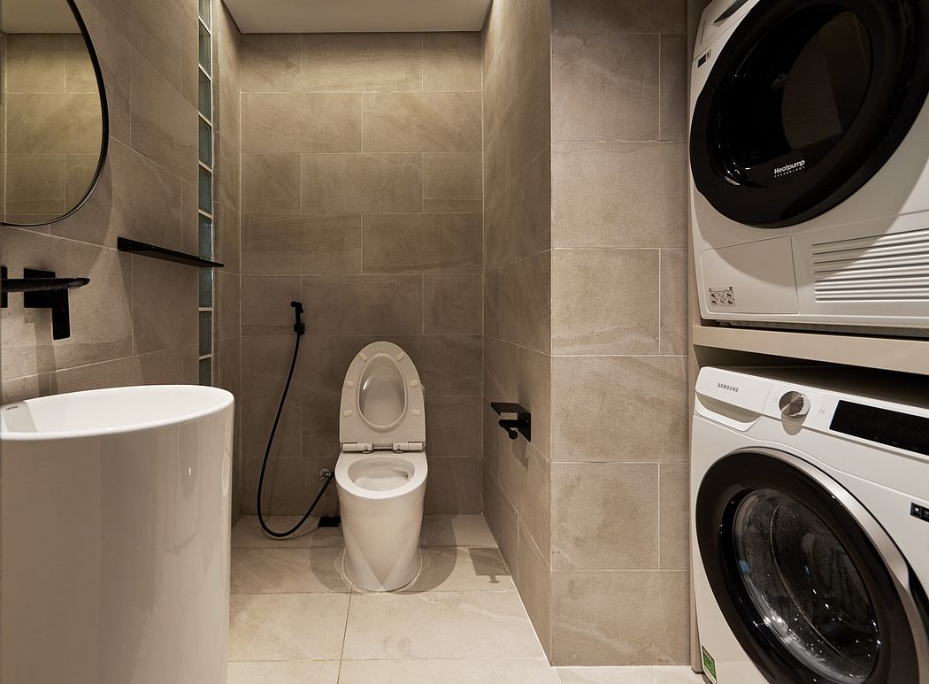 A modern bathroom with beige tiles, a toilet, and a washing machine in a corner.
