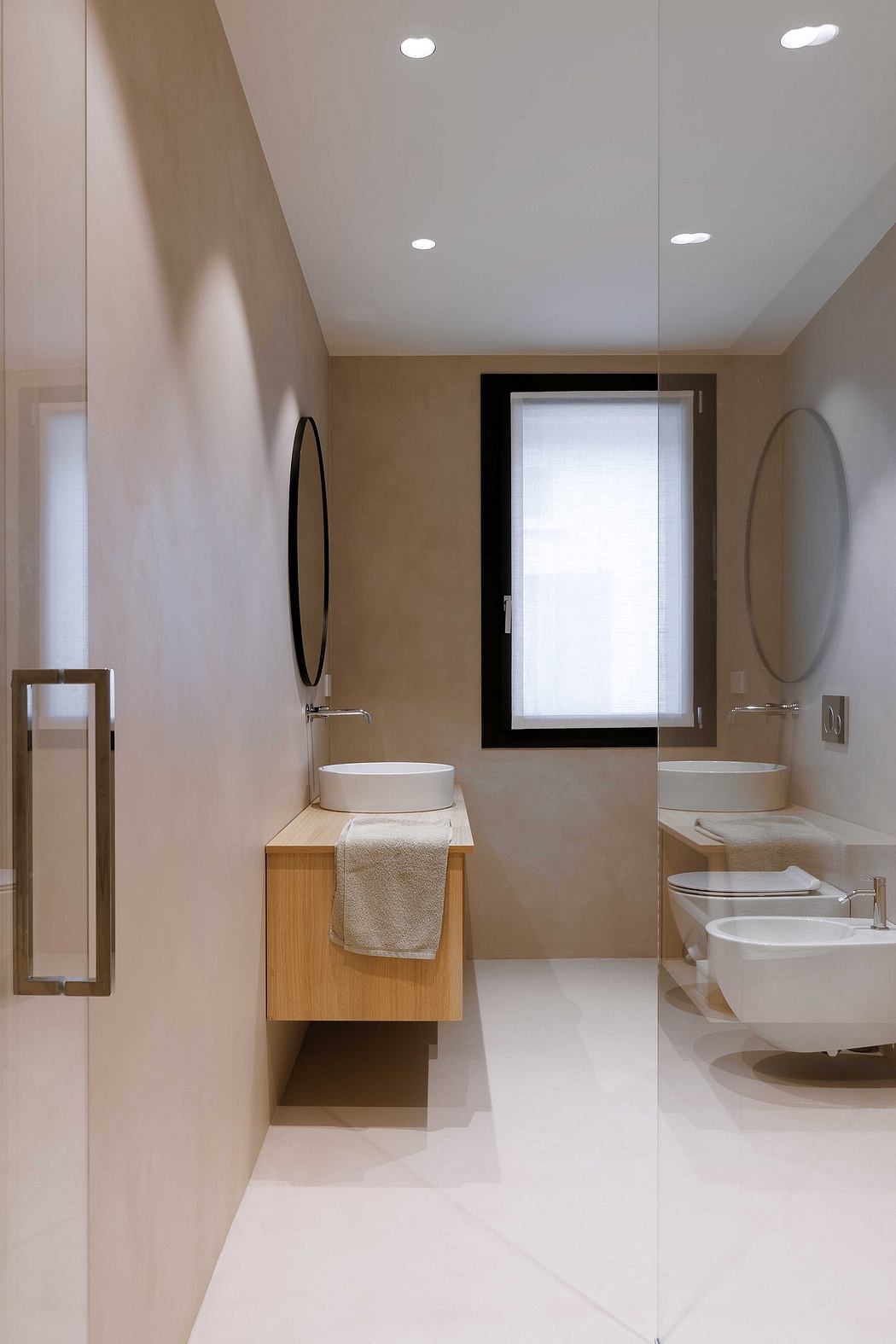 Modern bathroom with wooden vanity, round mirrors, and white fixtures.