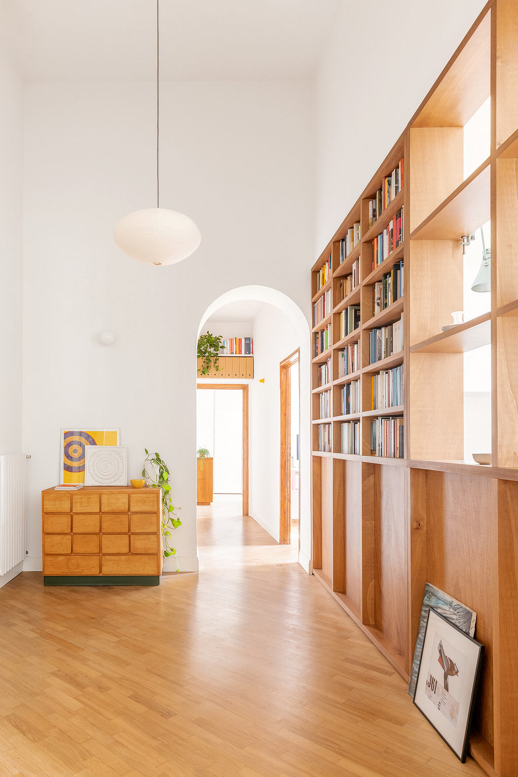 Bright hallway with wooden bookshelf, hardwood floor, and white walls.