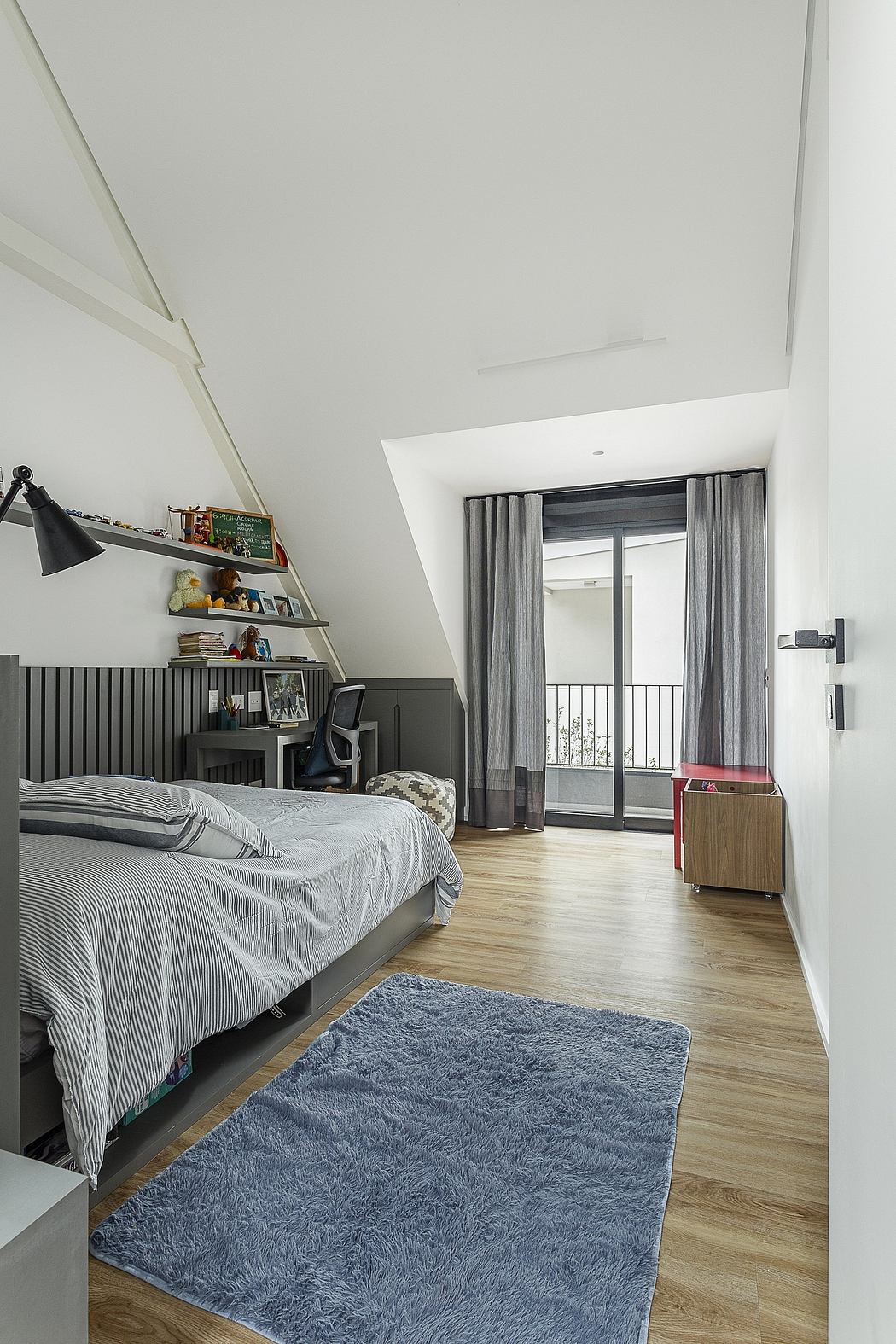 Contemporary bedroom with slanted ceiling and balcony access.
