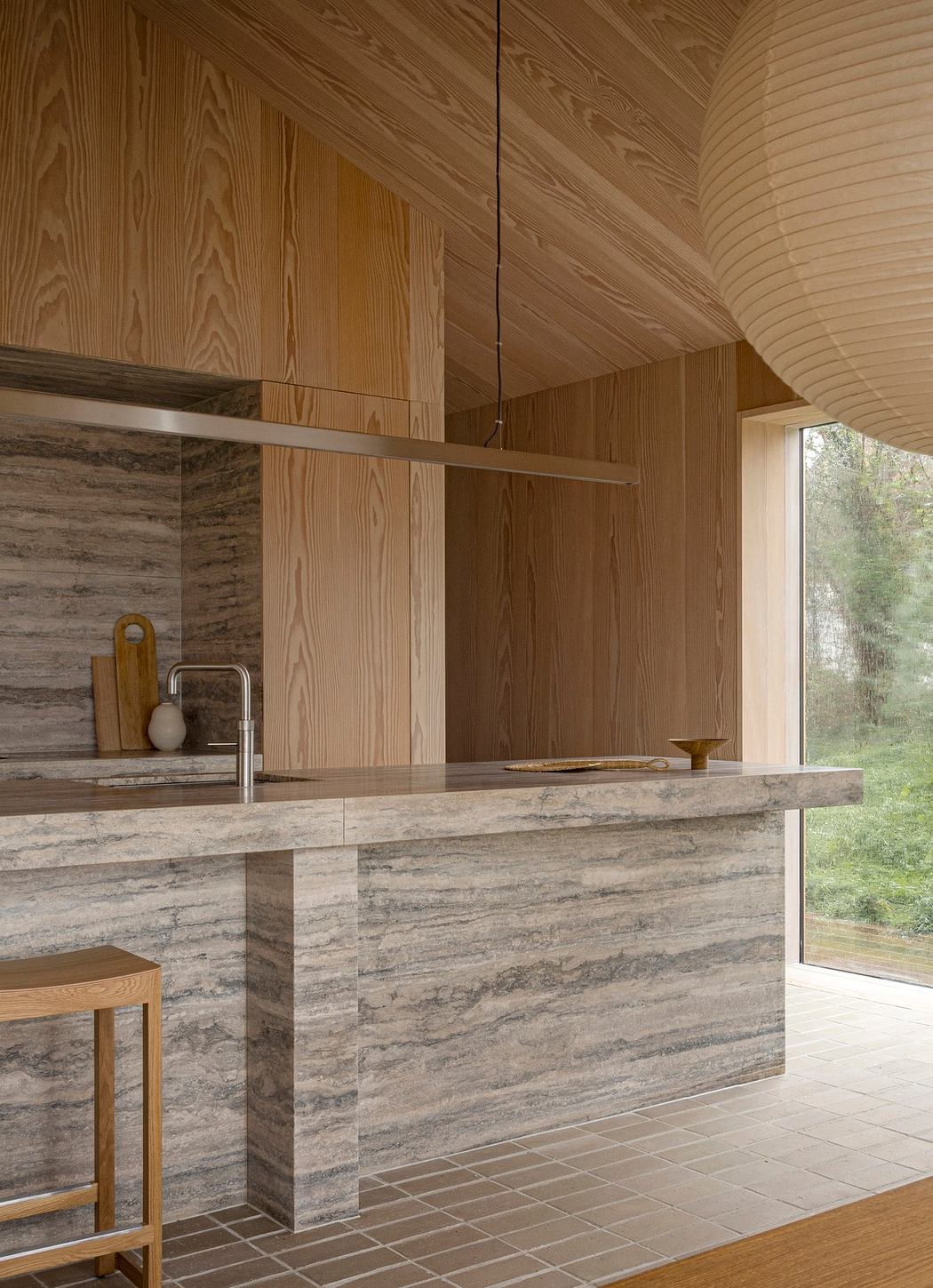 A minimalist wooden kitchen corner with marble countertop and large window.
