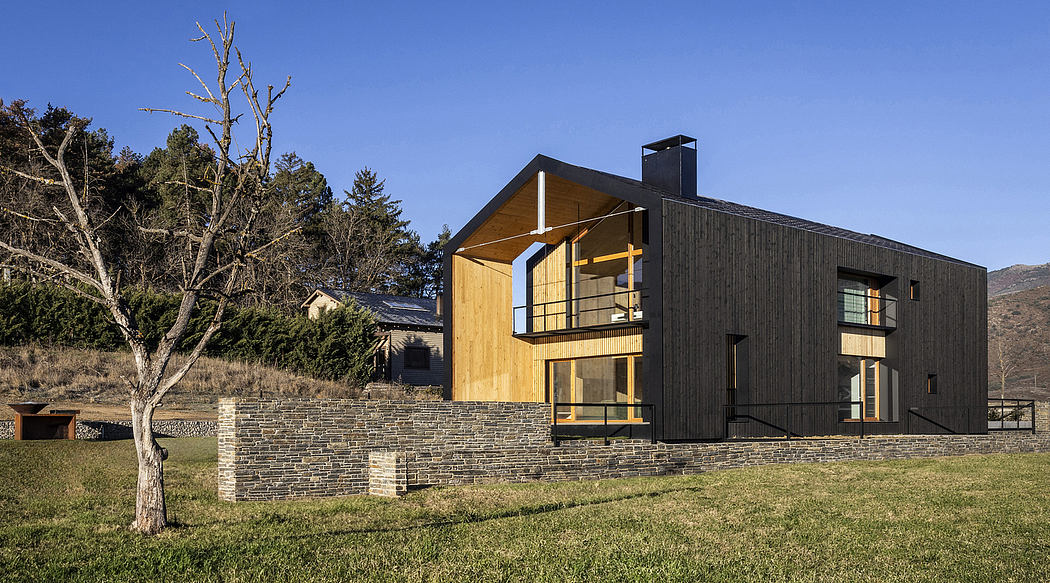 A modern, angular residence with extensive use of wood and stone, set against a mountainous landscape.