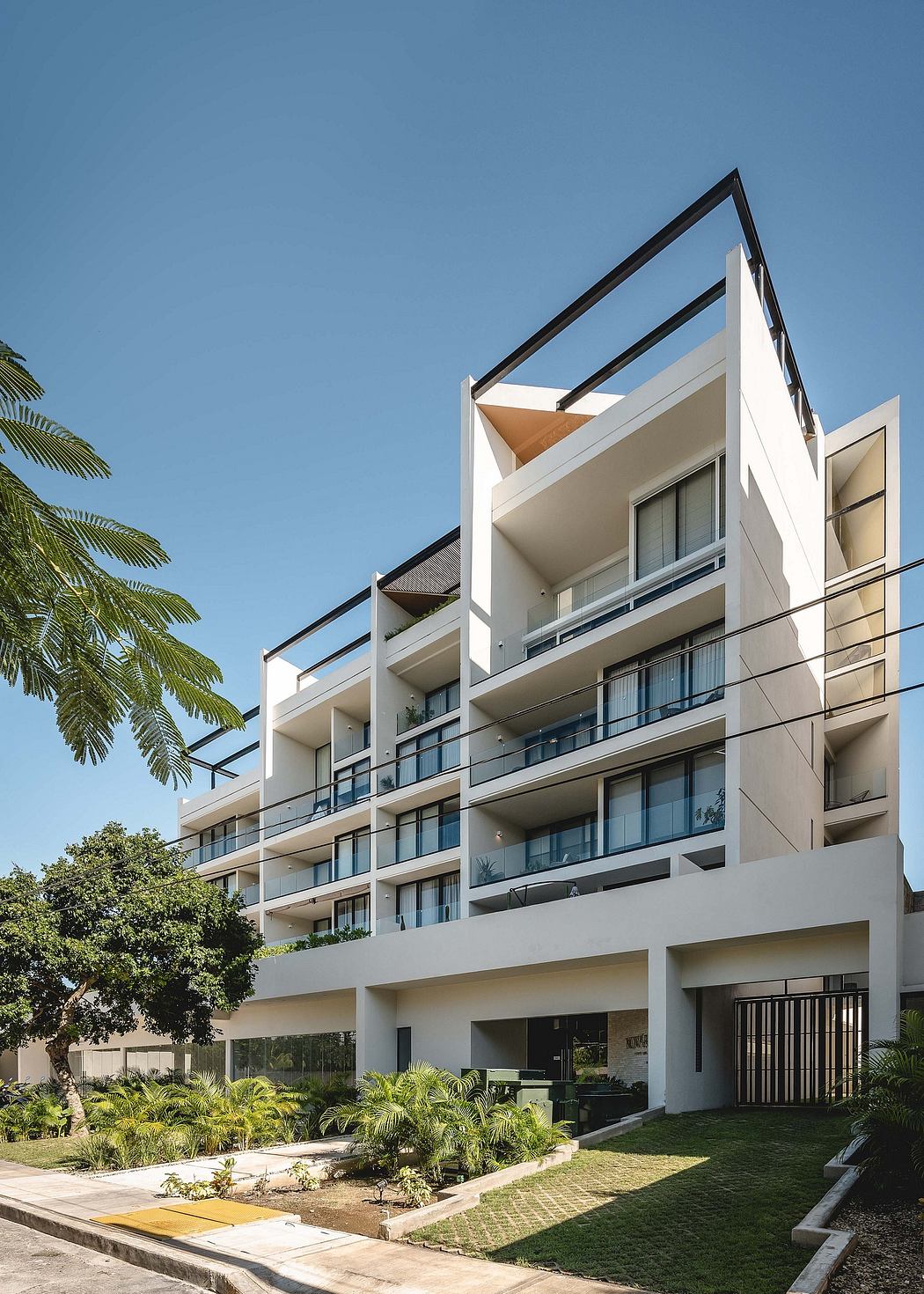 Modern multi-story residential building with balconies and clear blue sky.