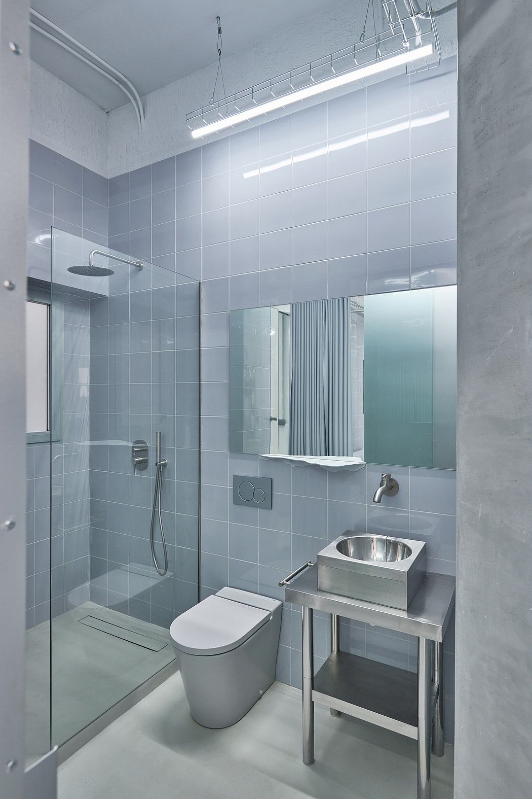 A modern, minimalist bathroom with sleek tile, a glass shower, and a stainless steel sink.