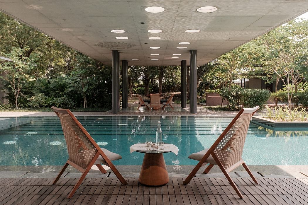 Sleek, modern pavilion with a swimming pool, wooden chairs, and a small table.