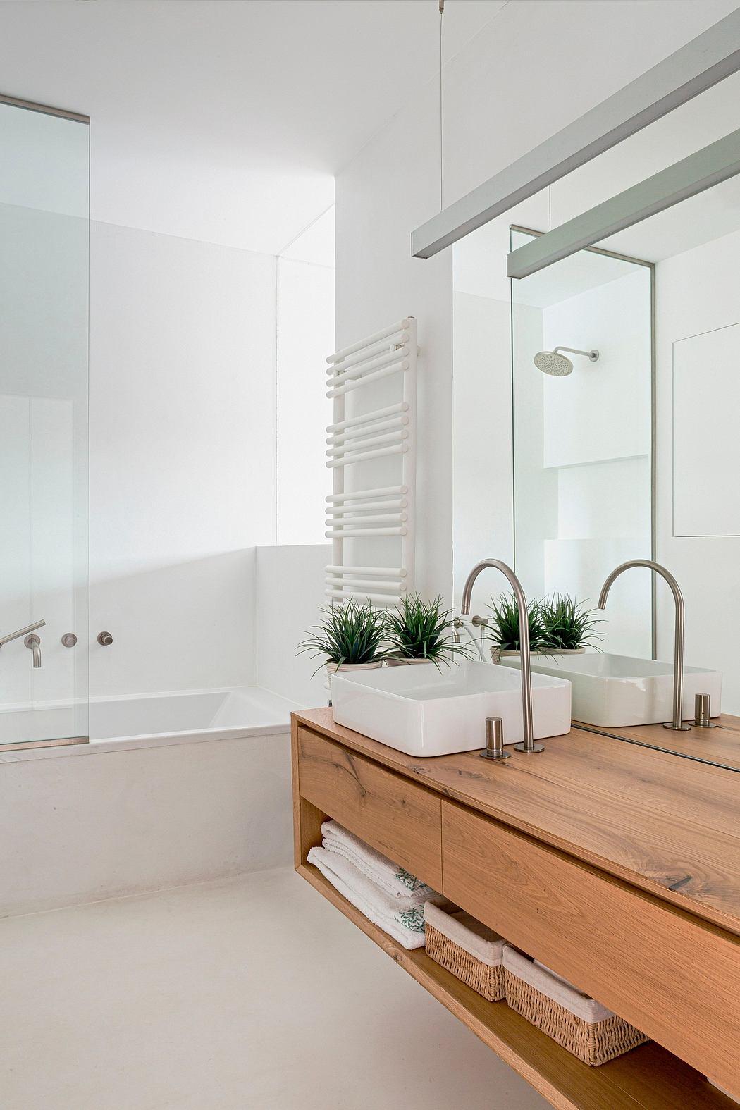 Minimalist bathroom design with white walls, wooden vanity, and potted plants.