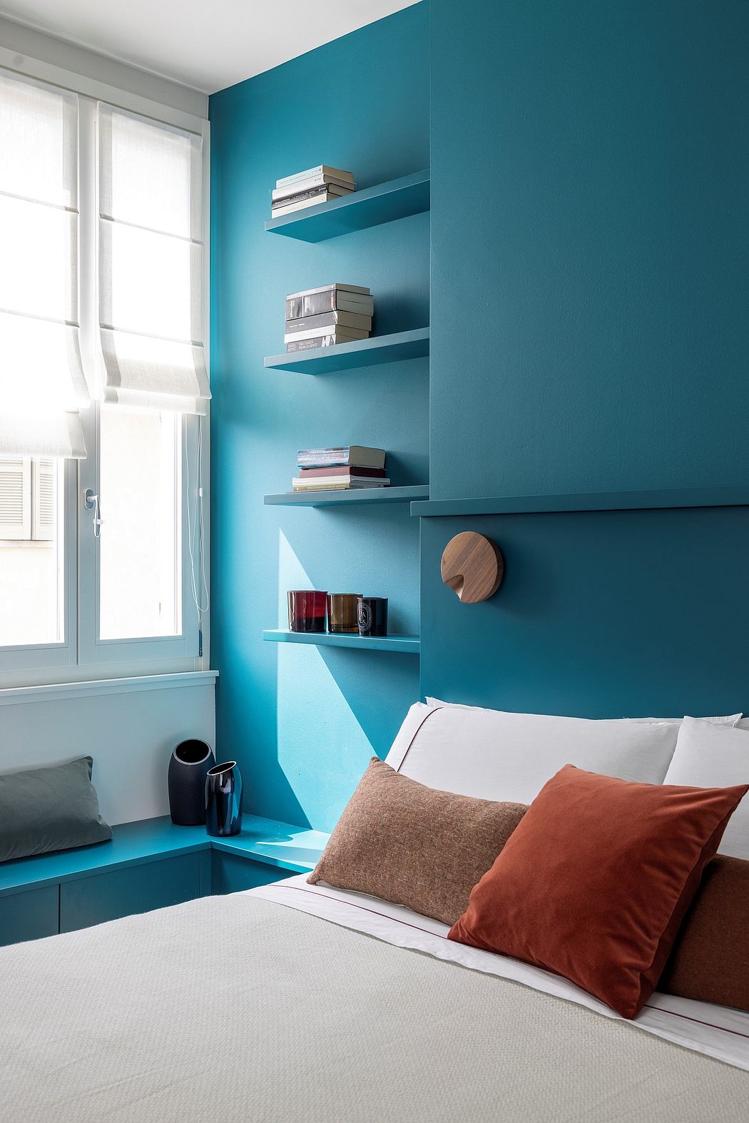 Vibrant teal walls, floating shelves, and cozy seating create a modern, inviting space.