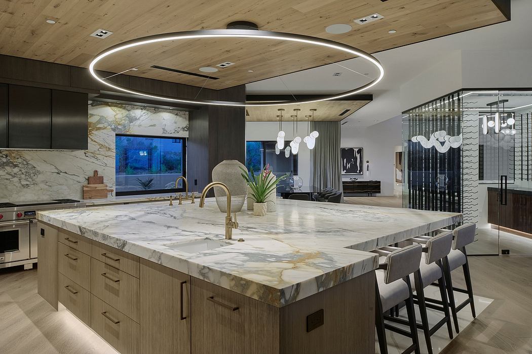 Spacious, modern kitchen with marble countertop, linear pendant lighting, and sleek cabinetry.