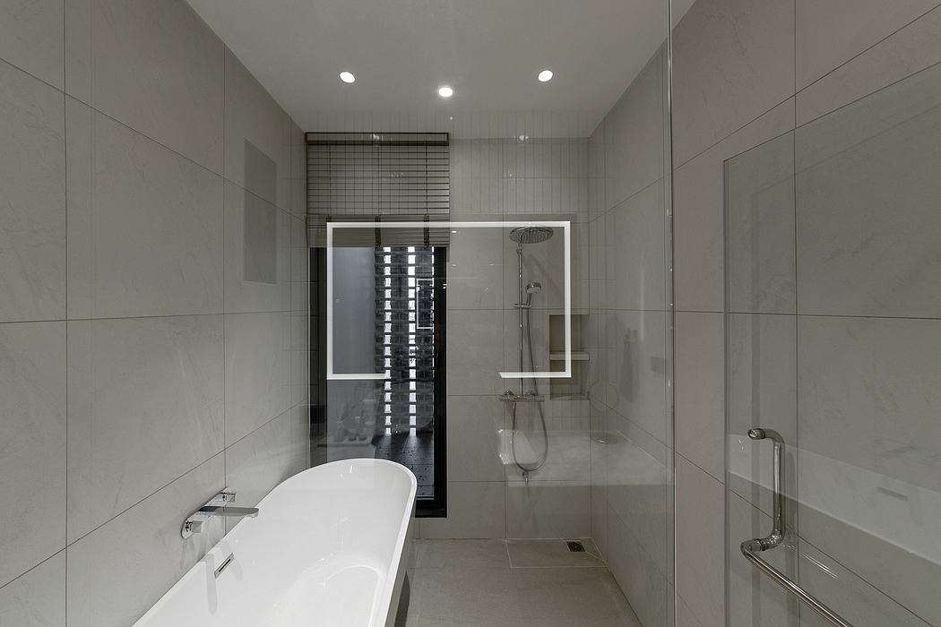 Contemporary bathroom with white tub, glass shower, and gray tiles.