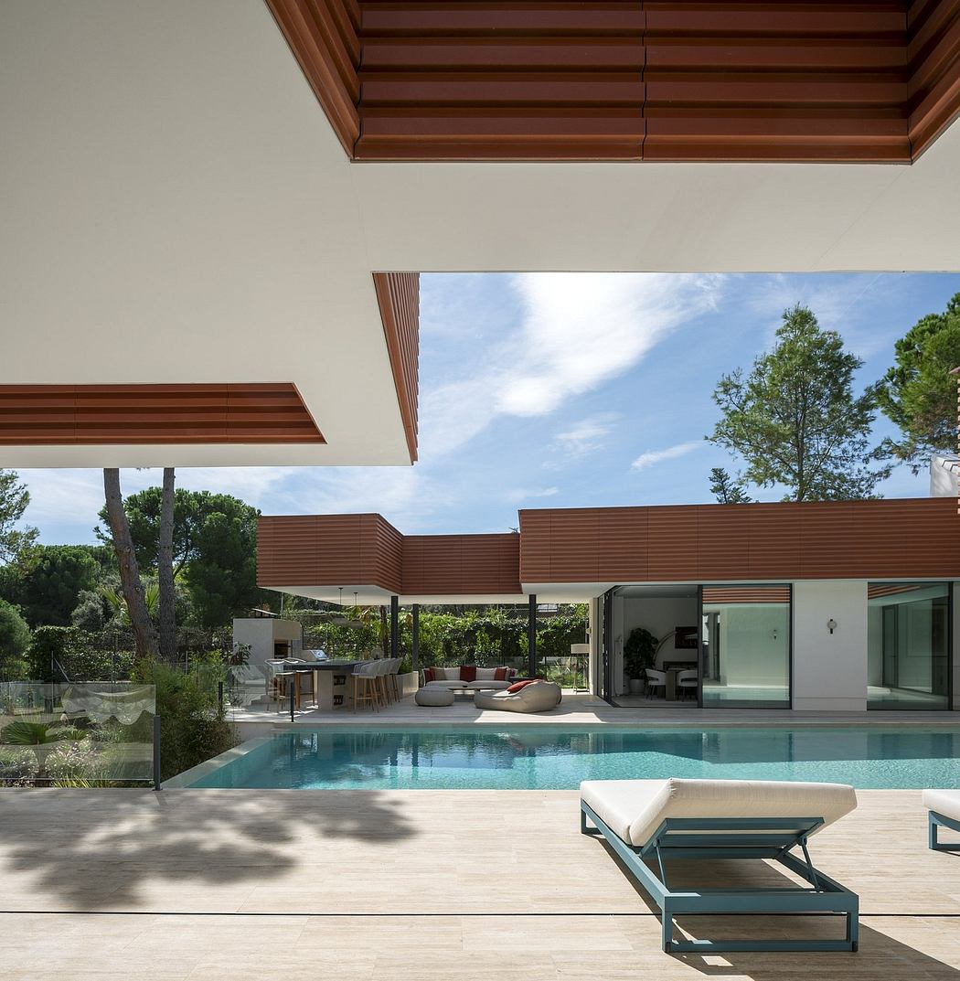 Sleek, modern architecture with a covered outdoor seating area overlooking a pool. Wooden beams and glass walls create an inviting, open space.