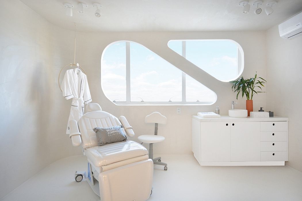 A modern, minimalist room with curved windows, a sleek treatment table, and a white cabinet.