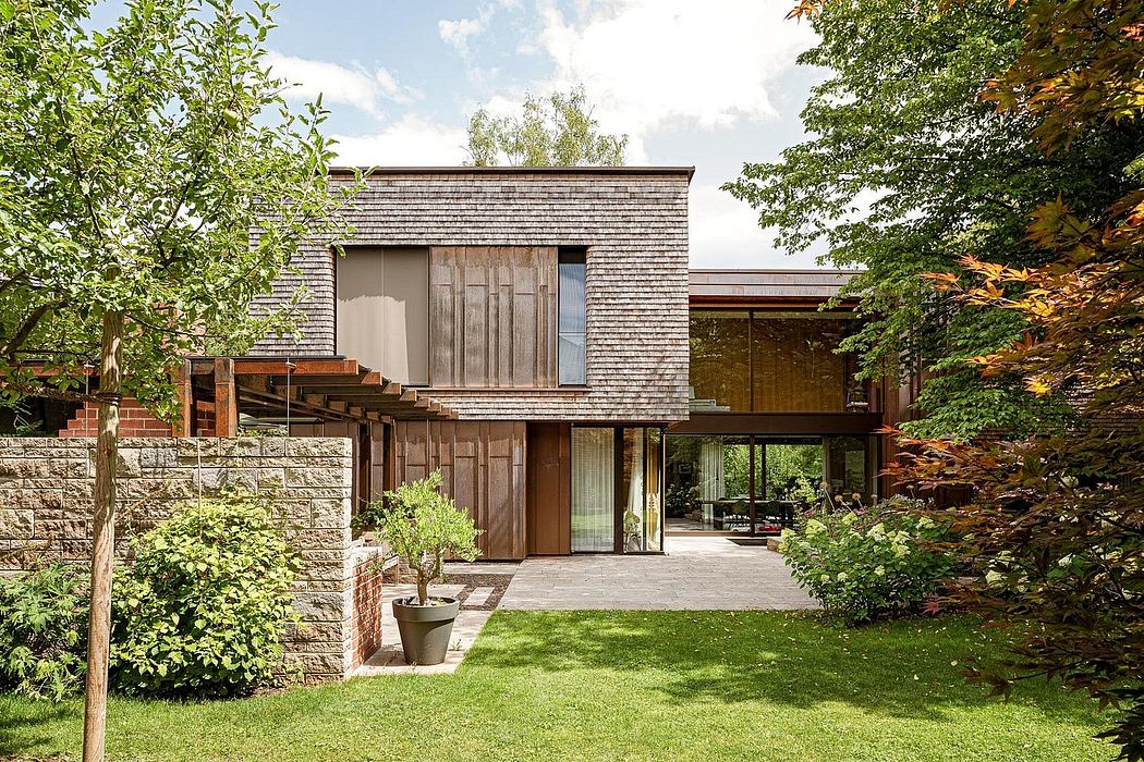Contemporary house with wooden slats, glass facade, and green lawn.