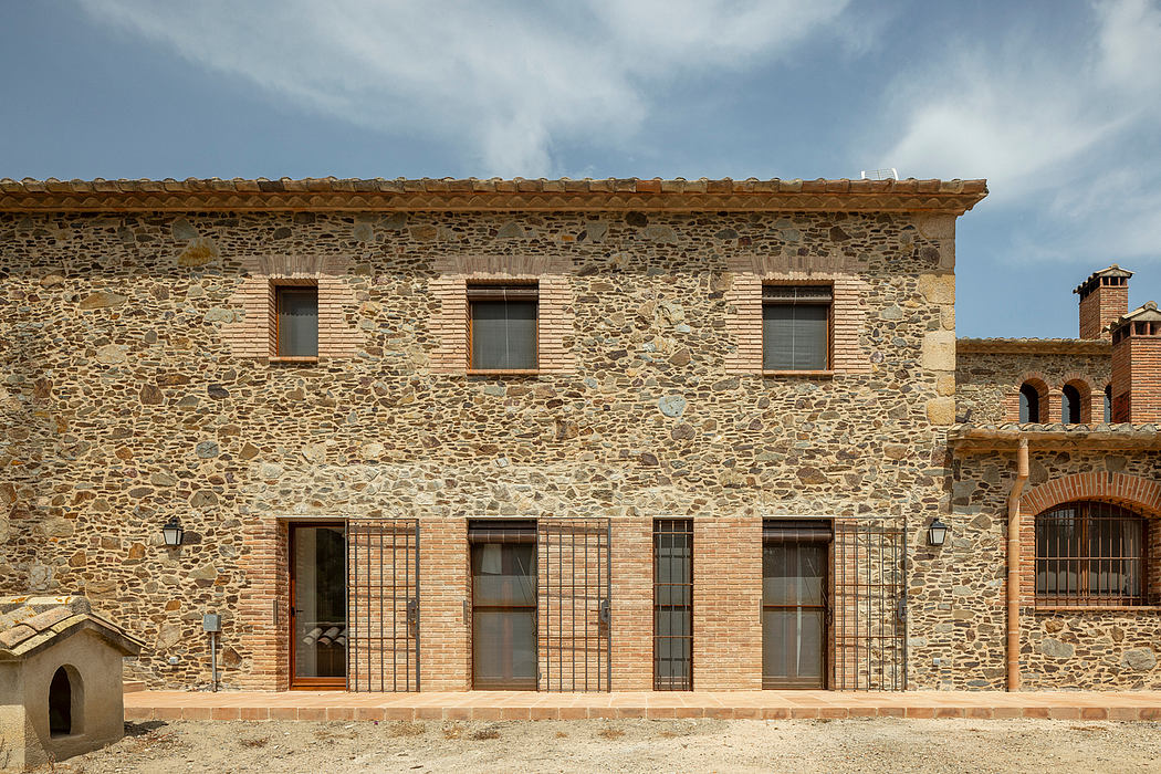 A stately, stone-walled building with arched windows and a tiled roof, evoking traditional architecture.