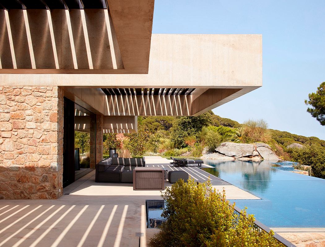 Modern house with an overhanging concrete roof, stone walls, pool, and