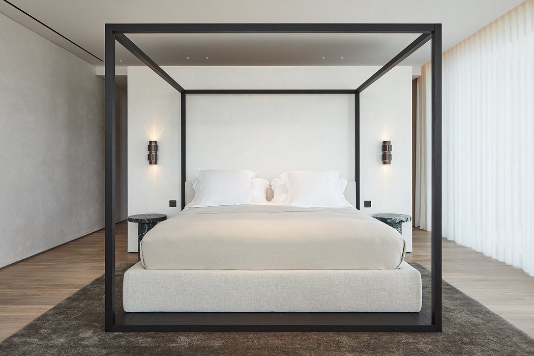 A modern, minimalist bedroom with a sleek, black four-poster bed frame and neutral-toned decor.