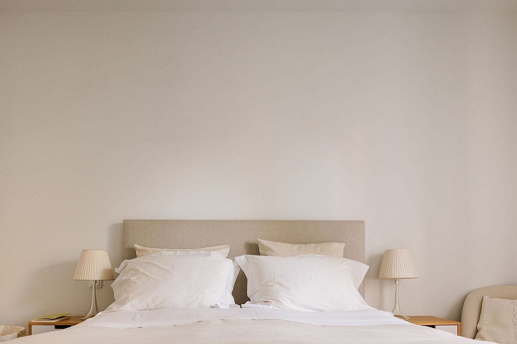Elegant neutral-toned bedroom with minimalist headboard and bedding, creating a calming ambiance.