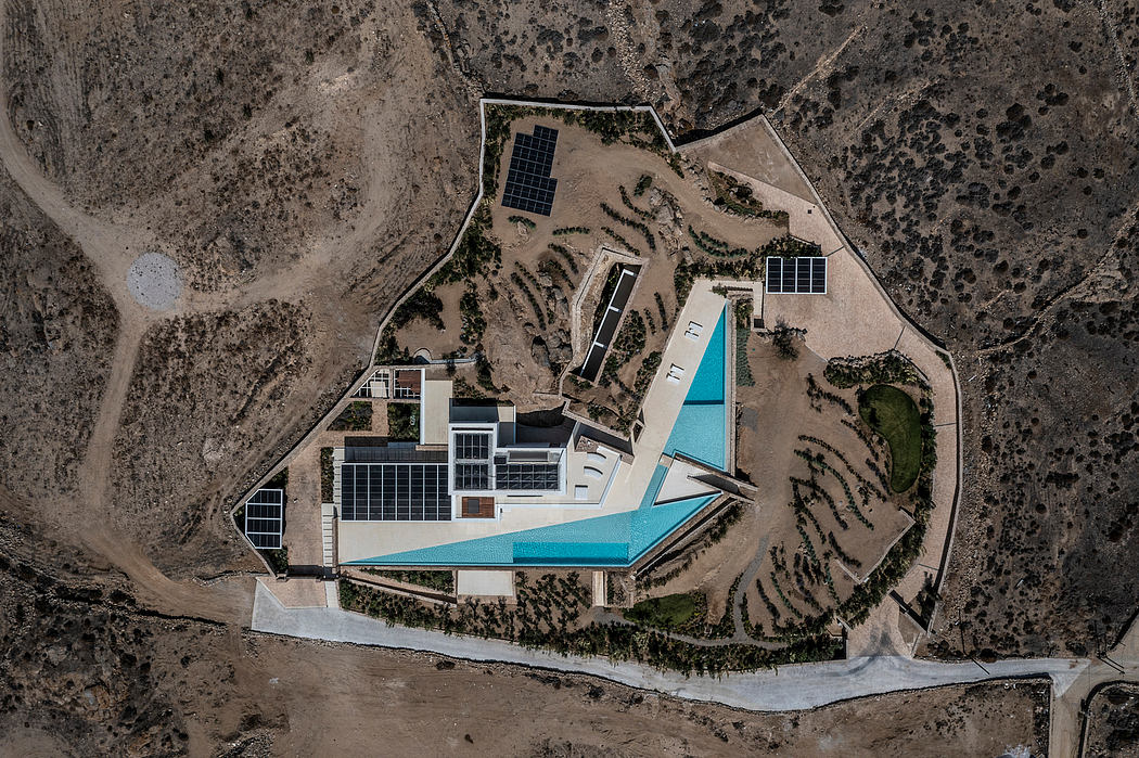 Aerial view of a modern house with a pool and solar panels in a desert