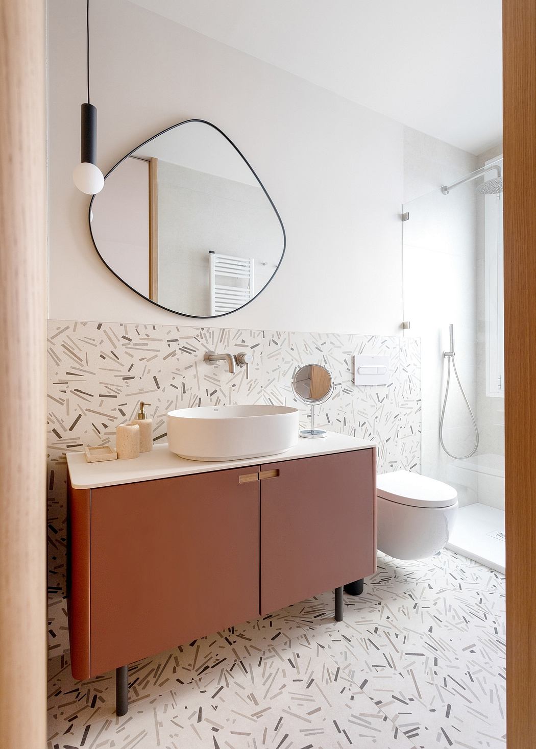 Minimalist bathroom design with a round mirror, vessel sink, and patterned tile floor.