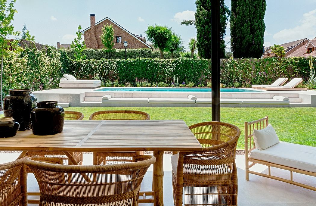 Cozy outdoor dining area with a wooden table and rattan chairs overlooking a swimming pool.