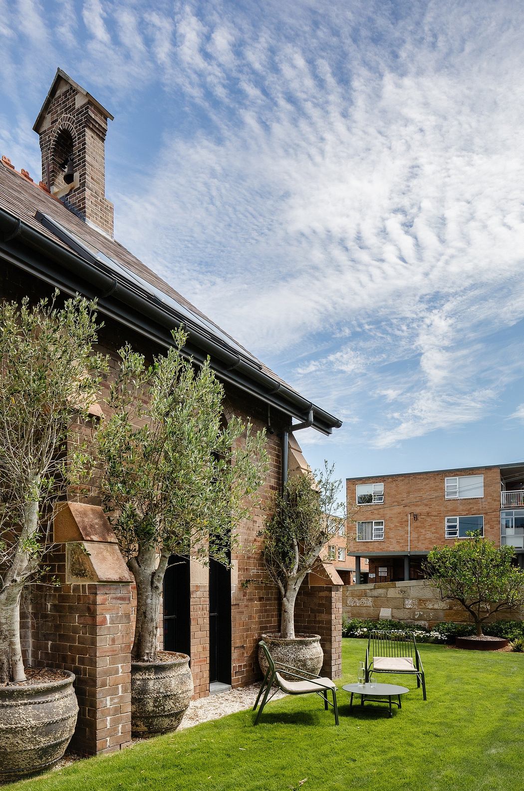 An inviting brick building with a chimney, surrounded by potted plants and outdoor seating.