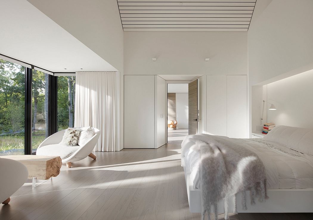 Minimalist bedroom with large windows, white decor, and wooden floor.