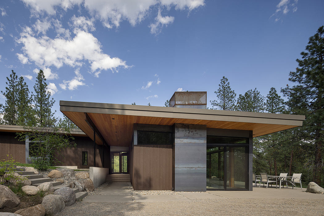 Modern house with large glass doors, overhanging flat roof, and surrounded by