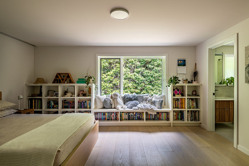 A cozy living space with built-in bookshelves, a window seat, and a peaceful, natural view.