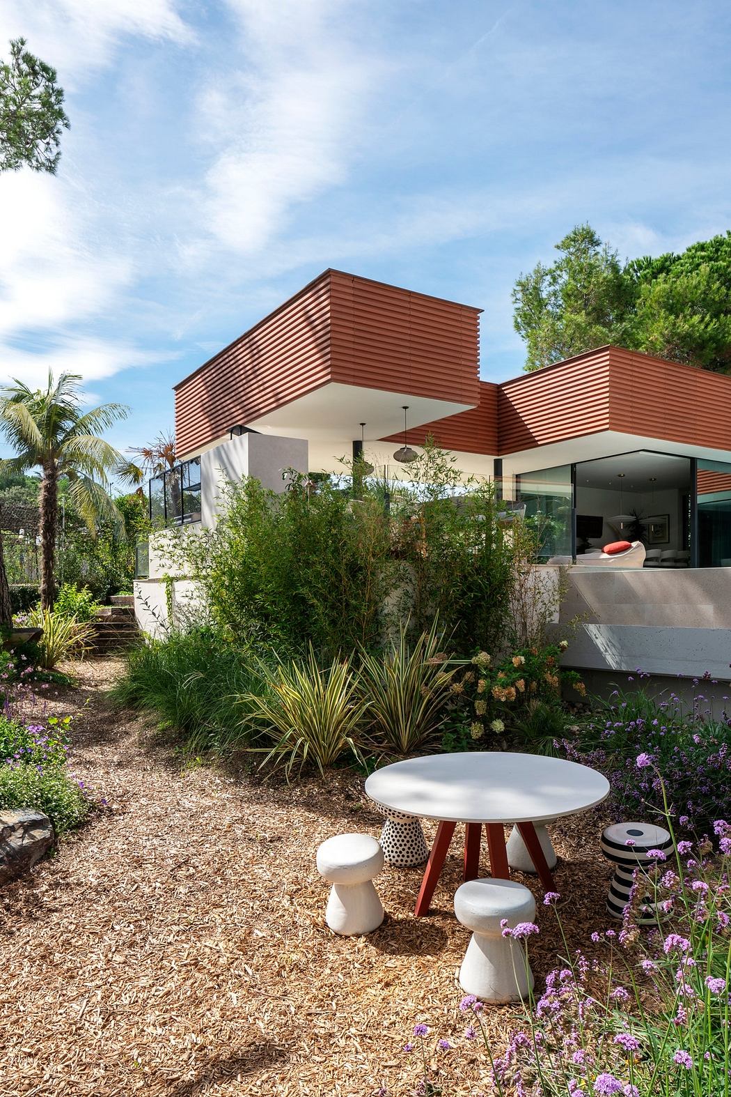 Striking modern architecture with a warm wooden exterior, surrounded by lush greenery.