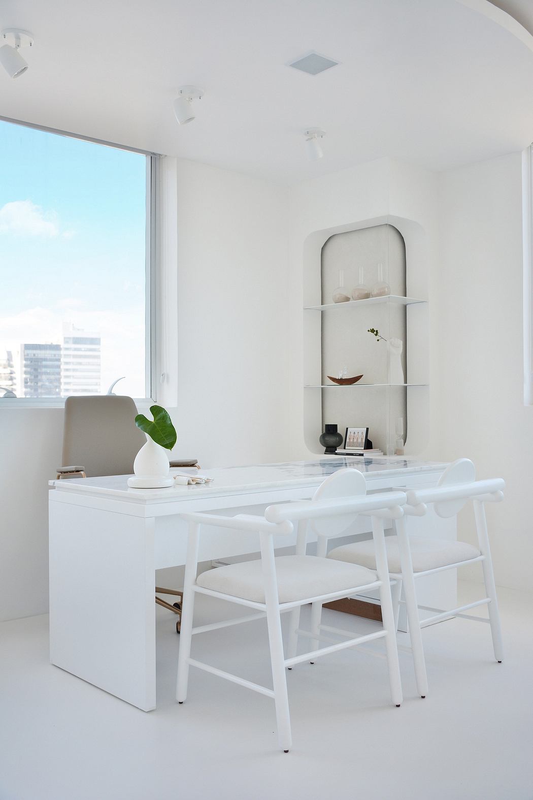 Sleek, minimalist office space with white table, chairs, and shelving unit; expansive window.