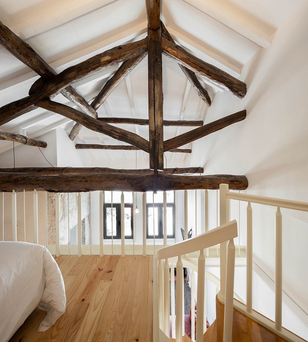 Rustic attic room with exposed wooden beams and white walls.