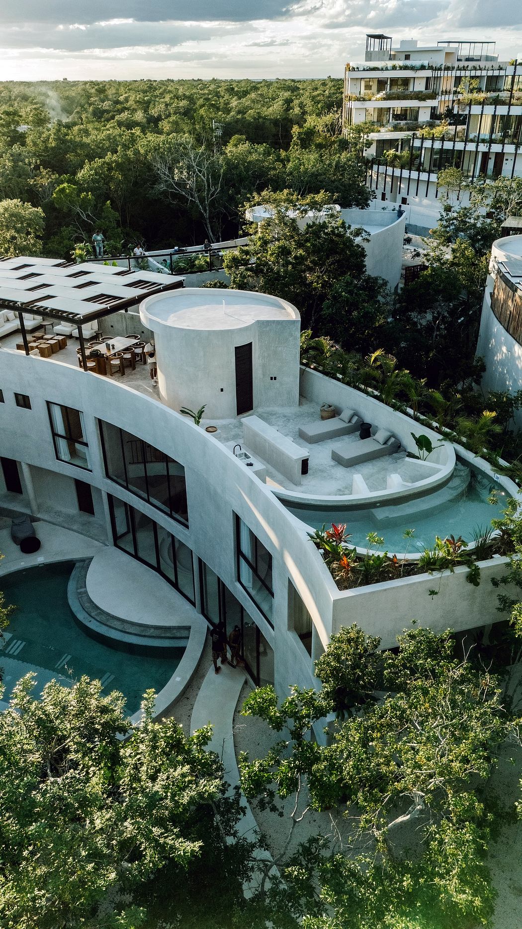 Modern building with curved design surrounded by trees.