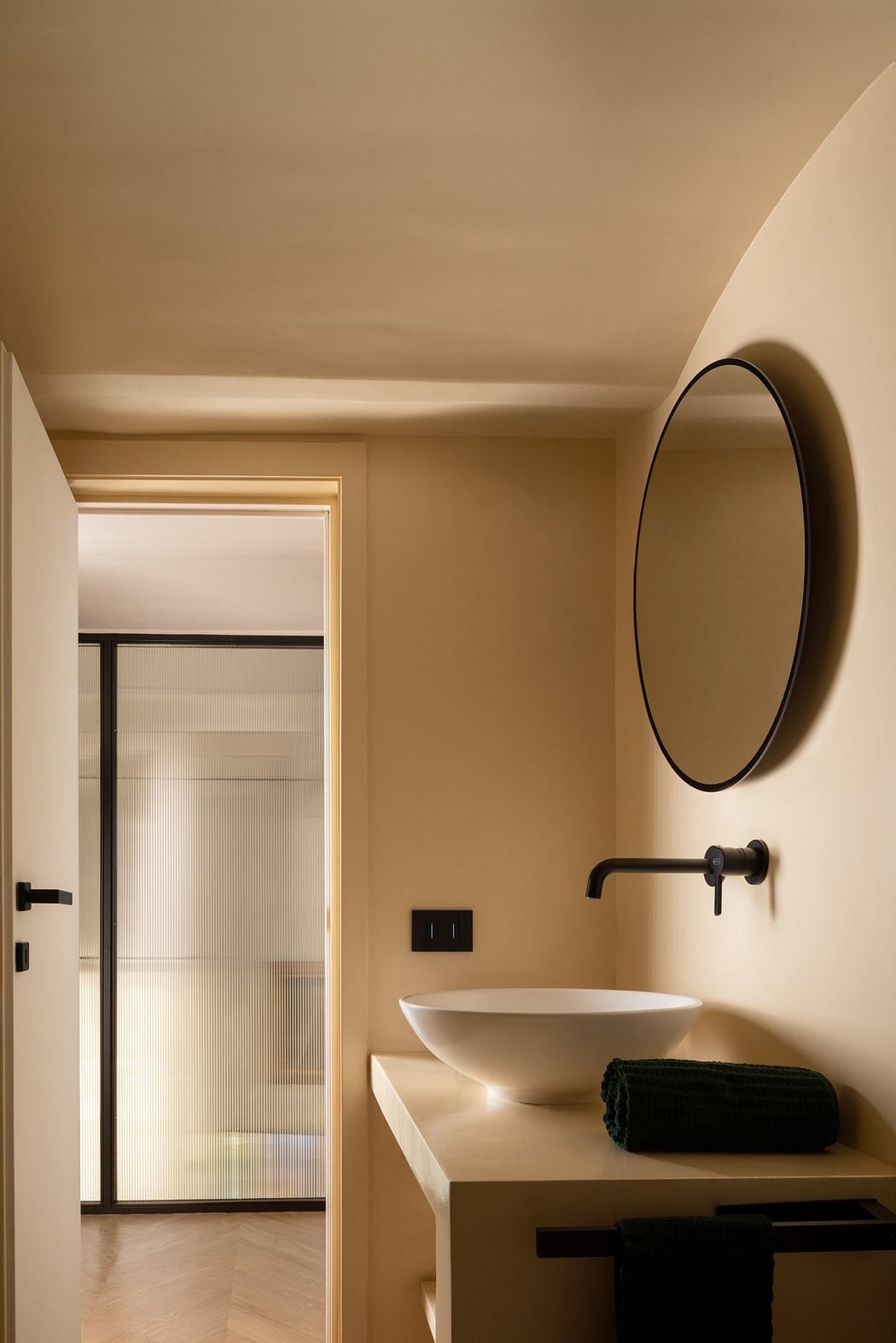 Minimalist bathroom interior with beige walls and a round mirror.