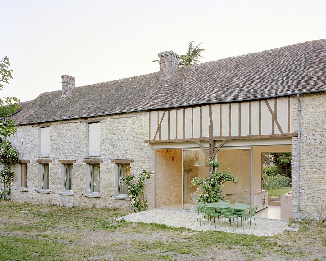 Traditional half-timbered house with a modern glass extension and outdoor furniture.