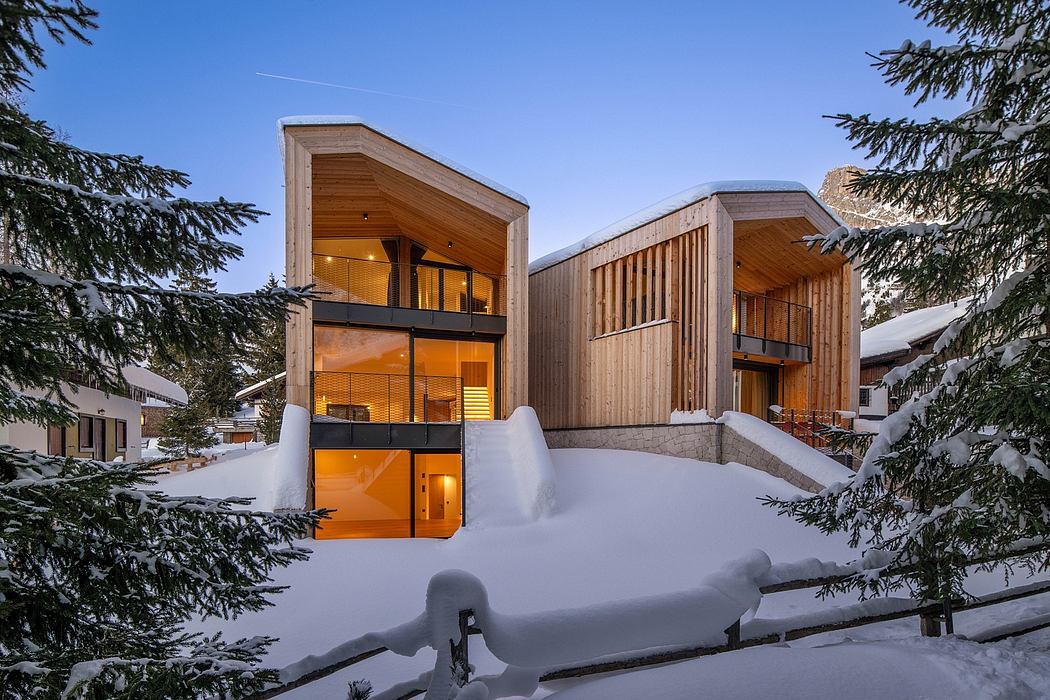 Striking modern wooden chalets with large windows and balconies, surrounded by snowy trees.