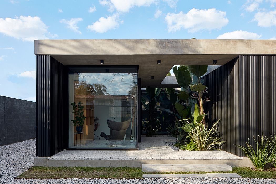 Modern house facade with large glass door and tropical plants.