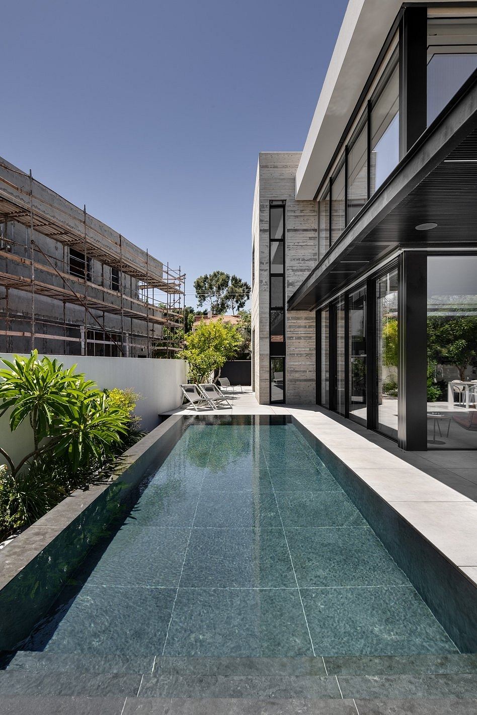 Sleek, modern architecture with a long narrow pool, lush greenery, and minimalist decor.