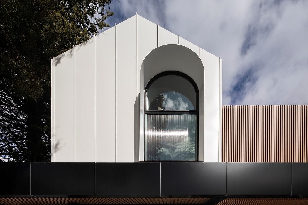 A modern, minimalist pavilion-like structure with a large arched window reflecting the sky.