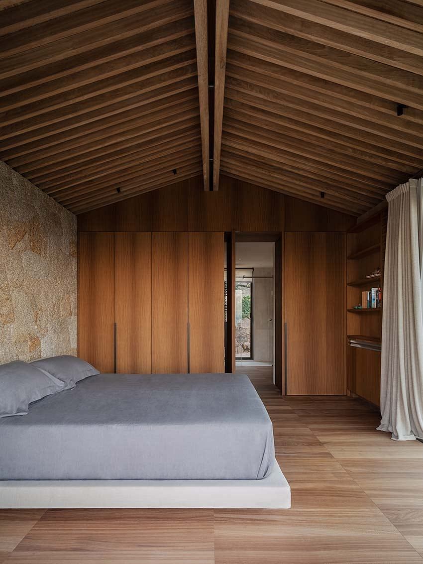 Modern bedroom with wooden paneling, slanted ceiling, and minimalistic decor.