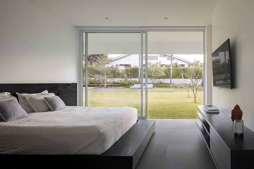 Minimalist bedroom with large windows overlooking a lush, grassy landscape.