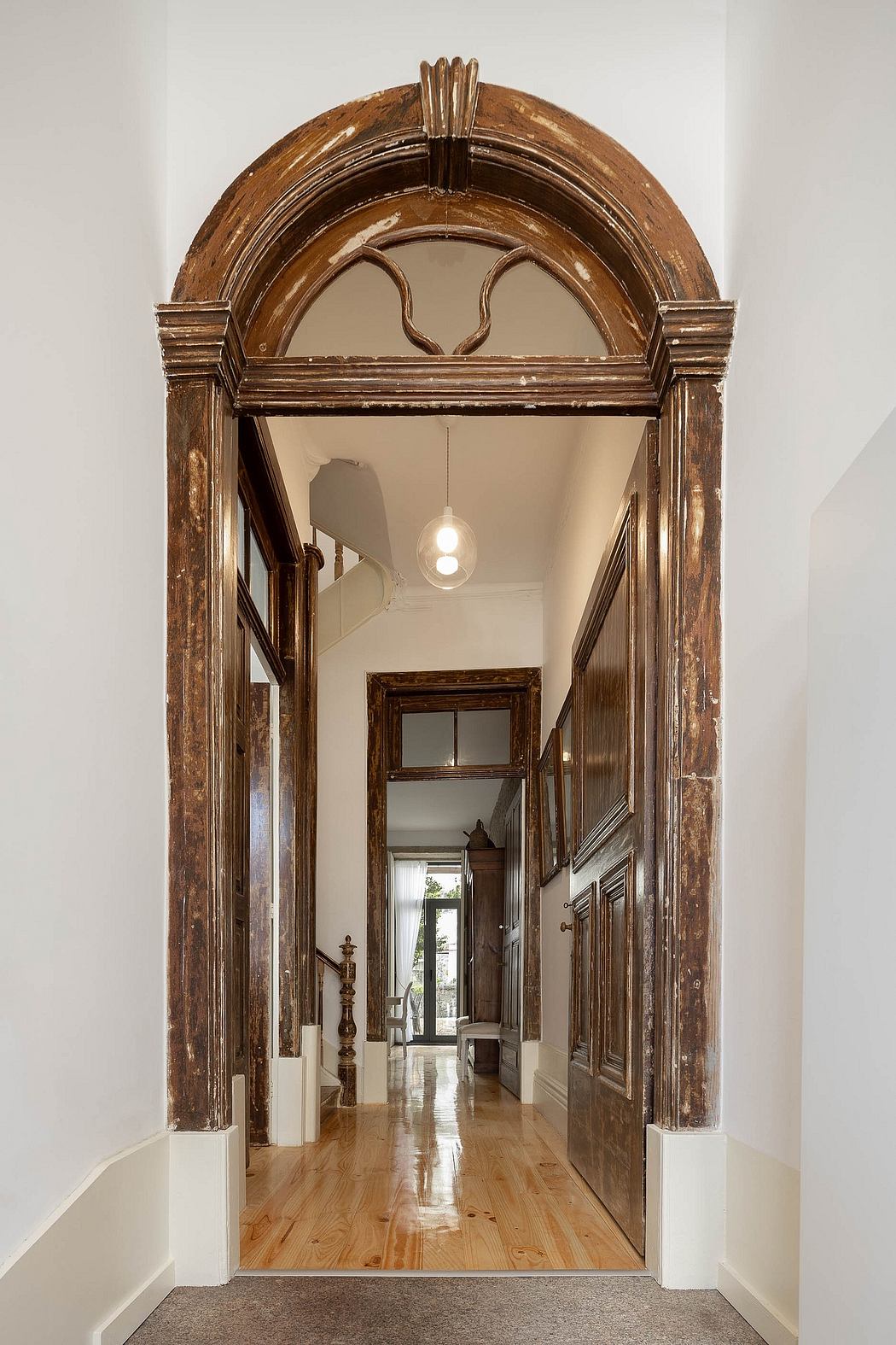 Elegant hallway with an arched wooden doorway and pendant lighting.