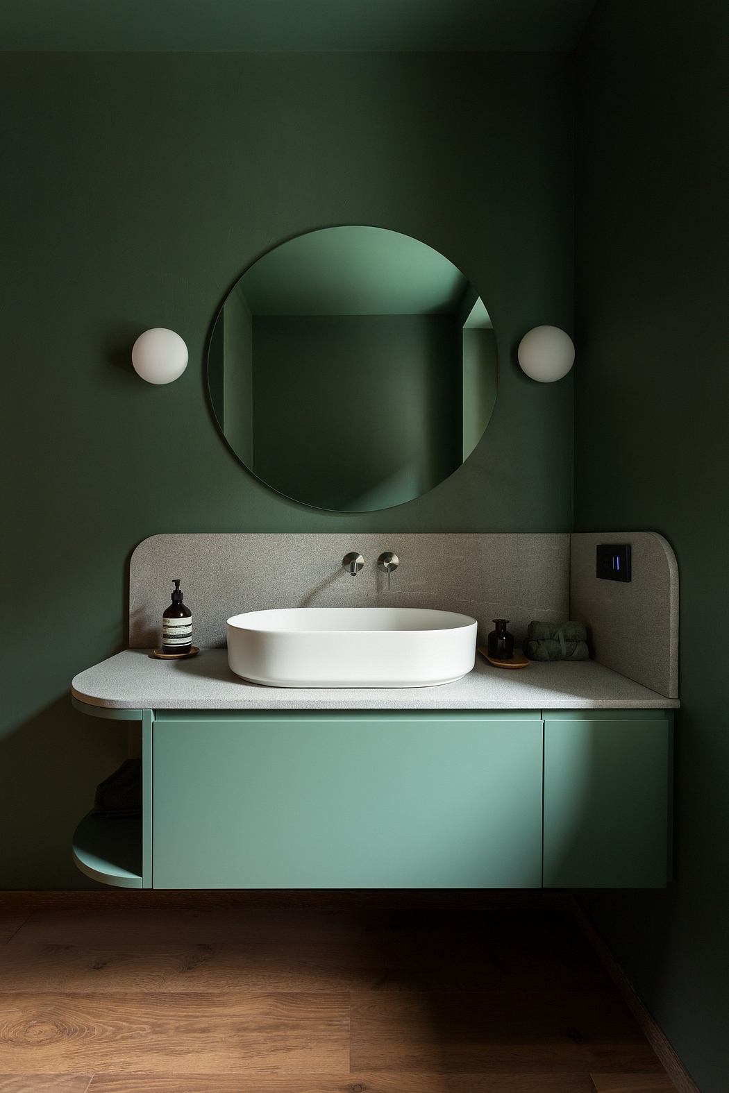Contemporary bathroom with a teal vanity, round mirror, and sleek fixtures.