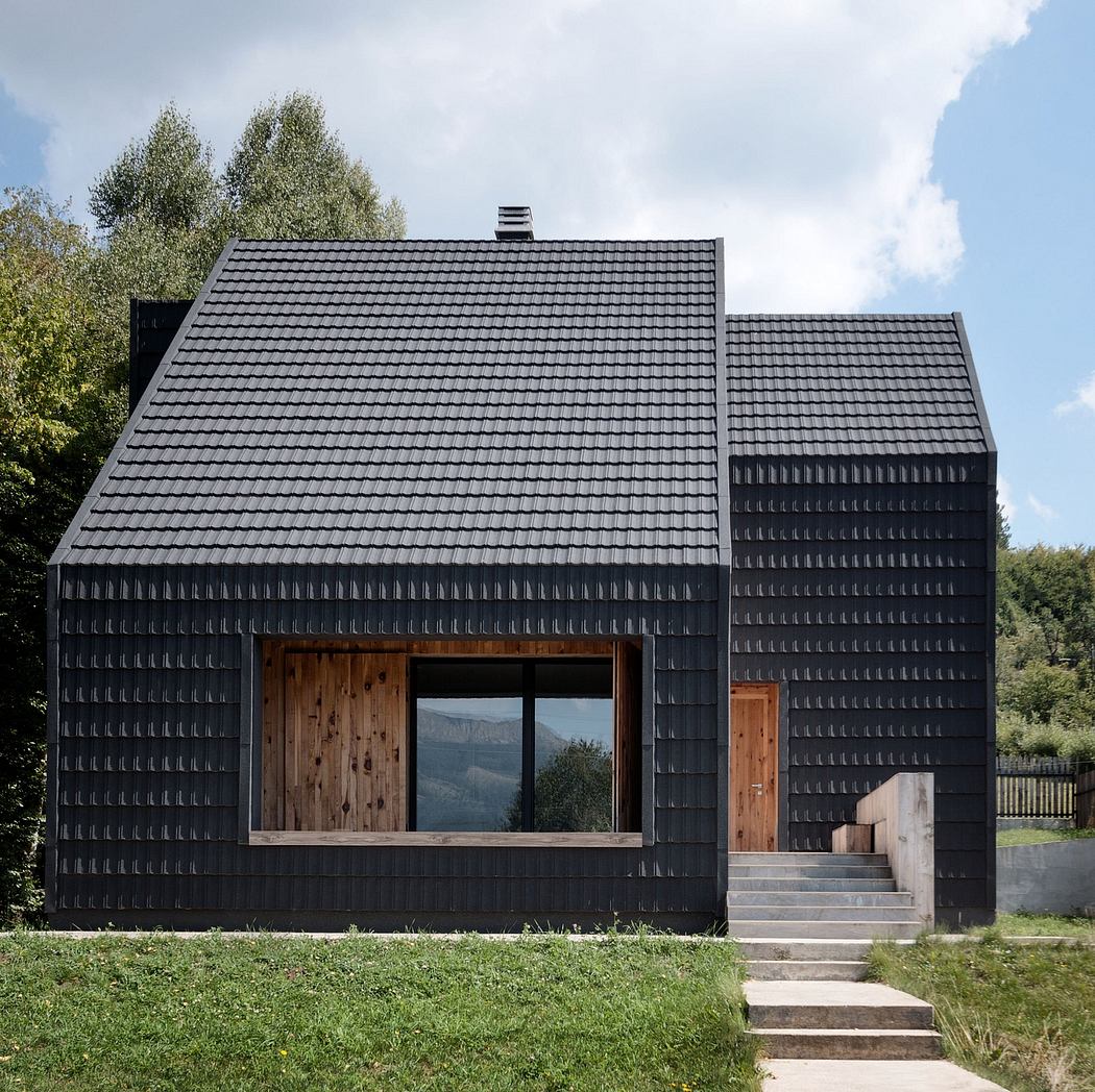 Modern cabin with black tiles, wooden accents, and large windows offering scenic views.