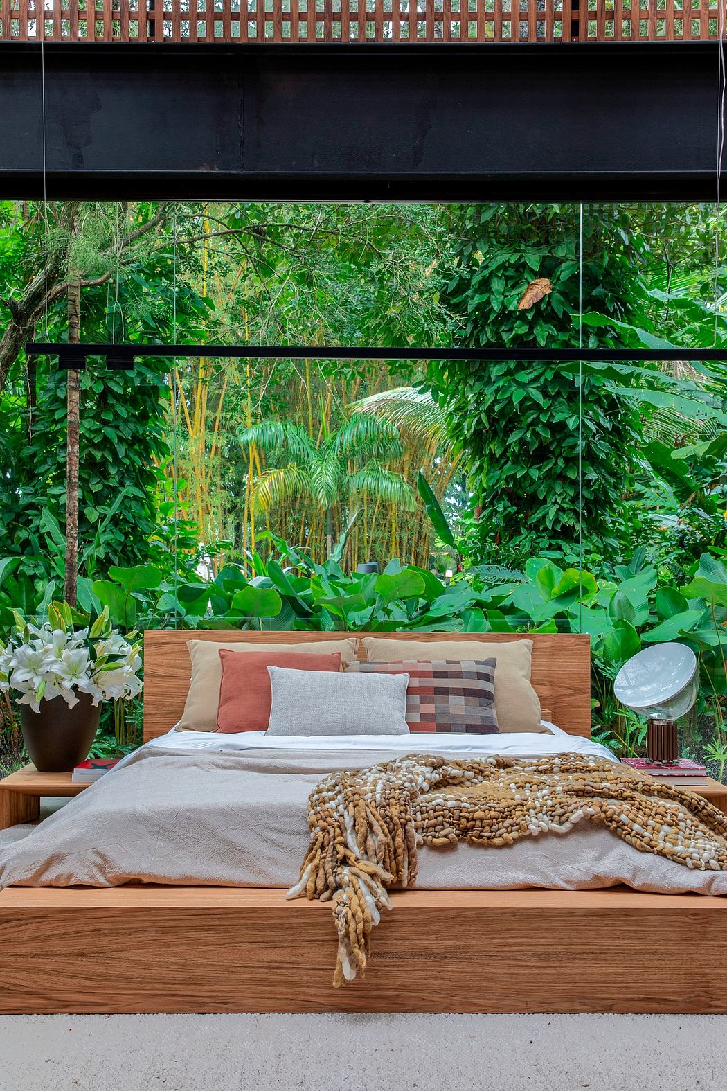 Modern bedroom with large window overlooking lush greenery.