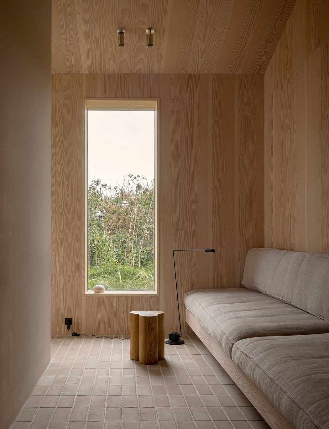 Minimalist wooden interior with a couch, window, and floor lamp.