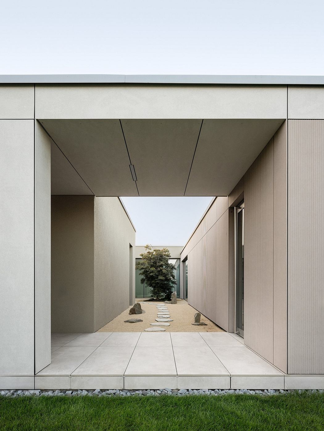 Modern building passageway with symmetrical design and centered tree.