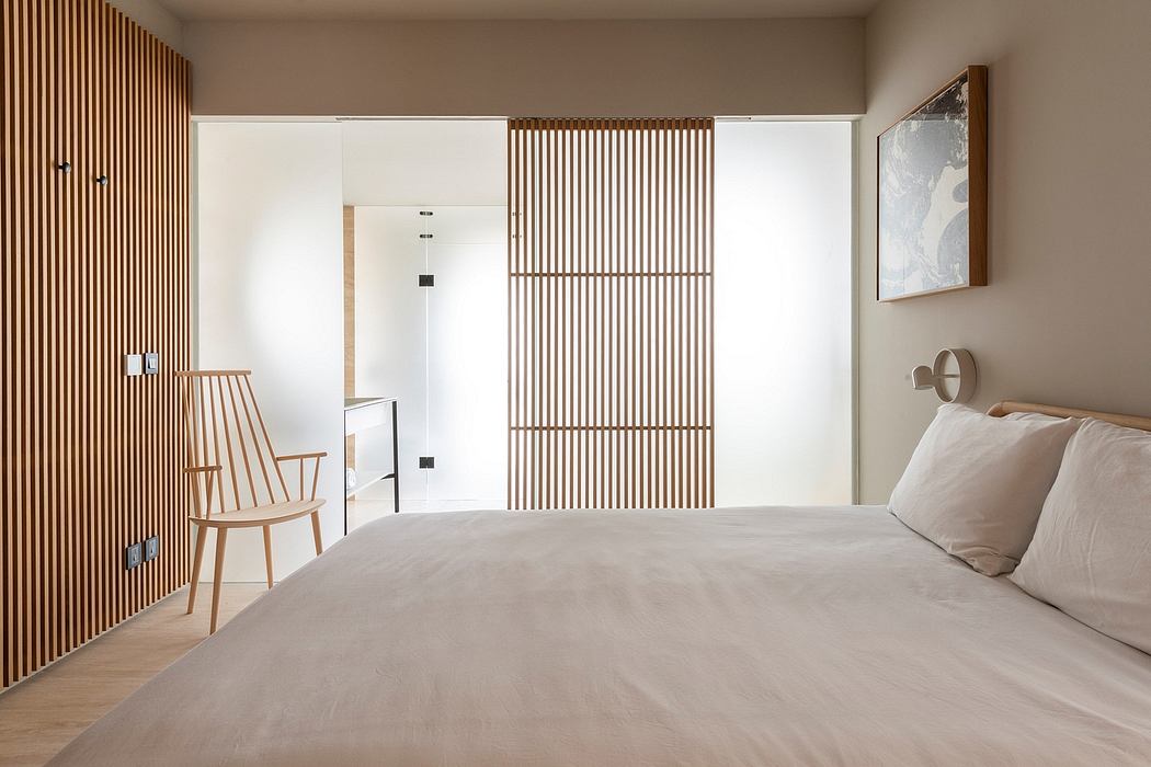 A minimalist bedroom with wooden slat paneling, a large window, and a cozy chair.