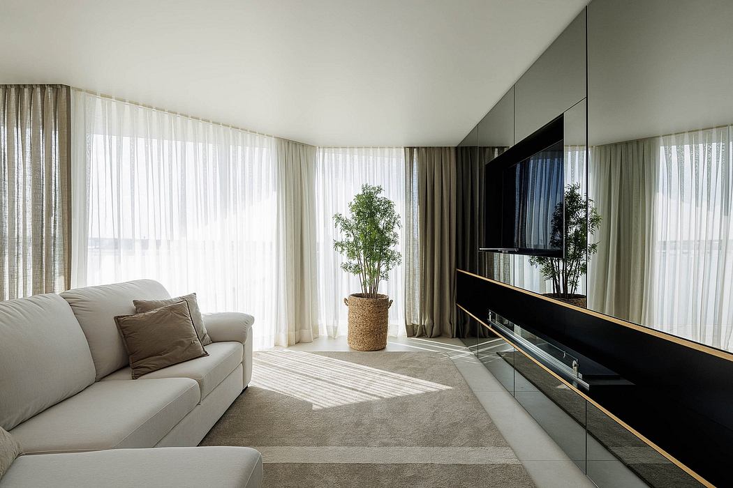 A modern, minimalist living room with large windows, neutral-toned furniture, and a sleek TV cabinet.