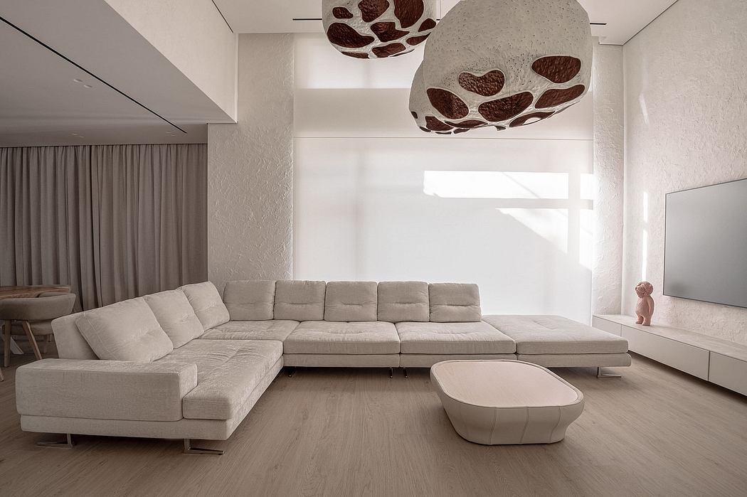 Minimalist living room with modular beige sofa, organic light fixture, and wood flooring.